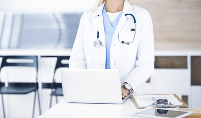 Unknown female physician using laptop computer, close-up. Woman-doctor at work in clinic. Medicine concept