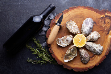 Fresh closed oysters, ice and lemon on a round plate, stone textured background.