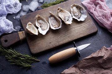 Fresh opened oysters, ice and lemon on a stone textured background.