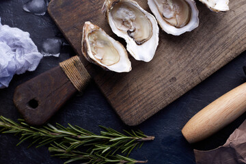 Fresh opened oysters, ice and lemon on a stone textured background.