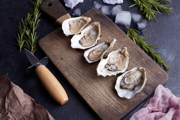 Fresh opened oysters, ice and lemon on a stone textured background.