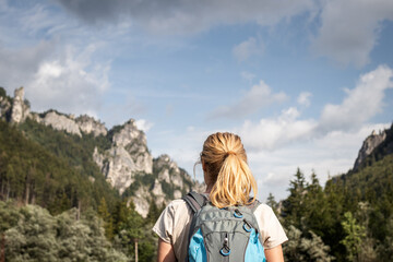 Naklejka na ściany i meble Hiker looking at rocky mountains. Woman with backpack hiking in nature
