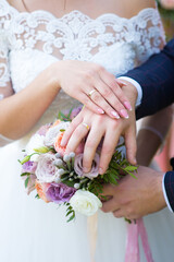 Hands of the bride and groom on the wedding bouquet