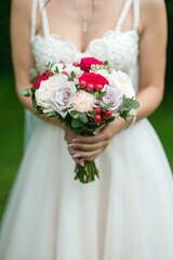 Bouquet in the hands of the bride of light and bright red roses
