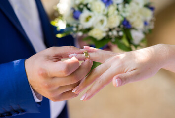 The groom puts a gold wedding ring on the bride's finger