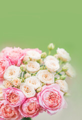 spring background with flowers. Bouquet with bush roses on a soft green background . Pink and cream roses in a wedding bouquet.