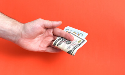 Hand holding folded money usa dollar on red background