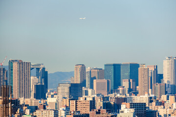 日本一の超高層ビル群、梅田方面の都市景観とその上を飛ぶ飛行機