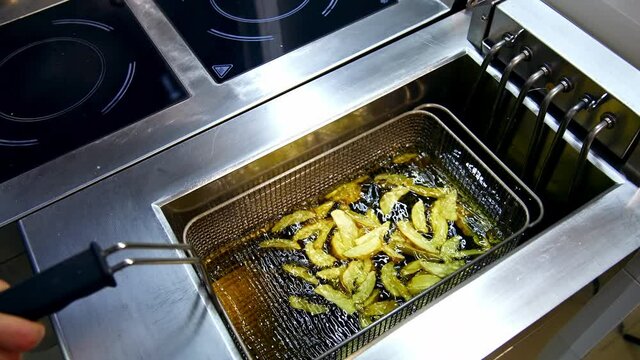 Cooking fries in deep fryer. Frying potatoes in restaurant fryer basket