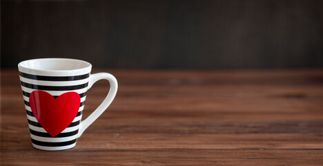 Stripy black and white cup with red heart on wooden background. Valentine's Day Cup. Love Concept