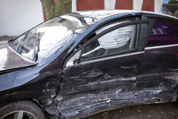 Black car after accident. Crashed vehicle close-up, side view, visible air bag. 