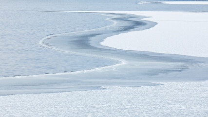 Fototapeta premium Partially frozen lake surface and snow