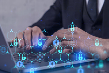 A programmer is typing a code on computer to protect a cyber security from hacker attacks and save clients confidential data. Padlock Hologram icons over the typing hands. Formal wear.