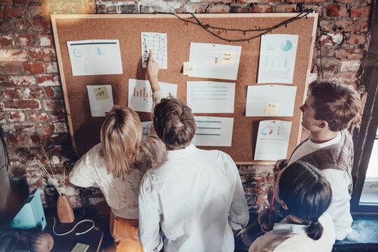 Office business team concept. Teamates standing near big wall desk and discovering new plans