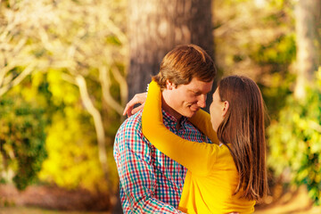 Close portrait of a young adults lovely couple hug outside in the park looking at each other