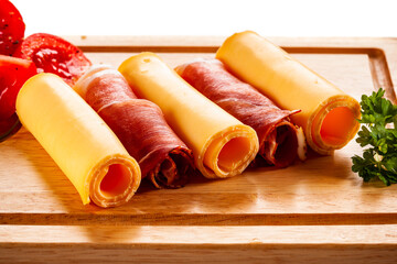 Yellow cheese and smoked ham on cutting board on white background
