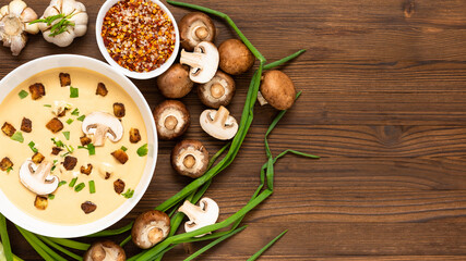 Mushroom soup with croutons, onions and spices. On a wooden background. Top view. Copy space.