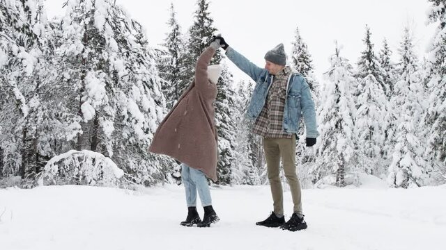 happy young couple dancing and having fun in winter forest