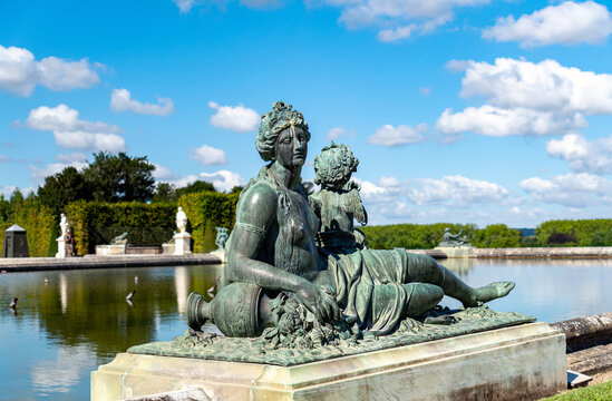 Versailles, France - July 07 2020: Statues in the Garden of the Royal Palace of Versailles - Bronze statue 'Nymphe et amour tenant un carquois' on the south pond (Water Parterre).