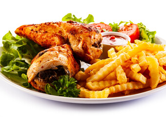 Stuffed chicken fillets, French fries and fresh vegetables
on white background