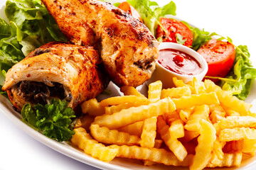 Stuffed chicken fillets, French fries and fresh vegetables
on white background