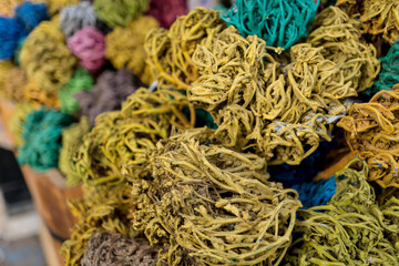 Colored dried seaweed shaped into decorative balls lays in the wooden baskets on the street market