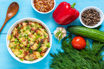 Tartiflette with bacon, herbs and vegetables over wooden blue background. Top view.