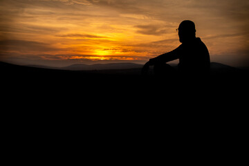 Fototapeta premium silhouette of a person sitting on a rock