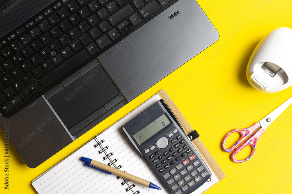 Wall mural top view of workspace with laptop note book scissors and tape on yellow background. work concept. flat lay flat design. finace concept