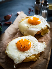 Continental breakfast - sunny side up eggs on baked bun with cheese and vegetable salad on black background
