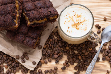 Morning cappuccino with chocolate cake. On a wooden background with coffee beans.