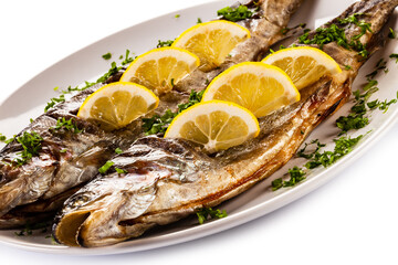 Fish dish - roasted trout with lemon on white background

