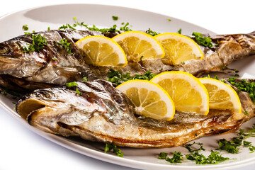 Fish dish - roasted trout with lemon on white background

