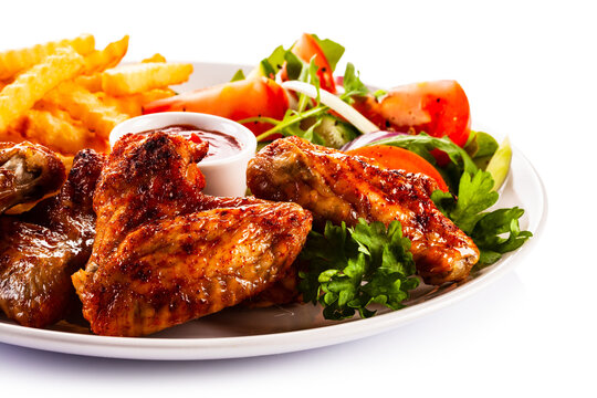 Roast Chicken Wings With Curly Fries And Vegetable Salad On White Background
