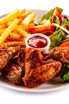 Roast Chicken Wings With Curly Fries And Vegetable Salad On White Background
