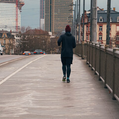 Jogger in Frankfurt crossing a bridge on a rainy winter day