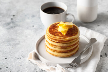 Stack of  fluffy pancakes   with butter and coffee cup on light background.American style breakfast.