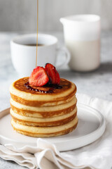 Fluffy American style Pancakes with maple syrup and strawberry  , cup of black cpffe on light background .
