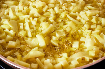 Chopped potatoes frying in extra virgin olive oil in the pan to make spanish omelet.