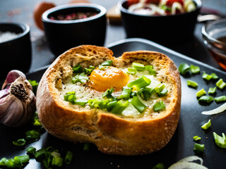Continental breakfast - sunny side up egg in baked bun with cheese and vegetable salad on black 