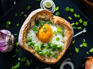 Continental breakfast - sunny side up egg in baked bun with cheese and vegetable salad on black 