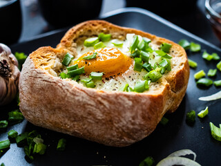 Continental breakfast - sunny side up egg in baked bun with cheese and vegetable salad on black 