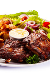 Tasty roasted ribs with baked potatoes vegetables on white background
