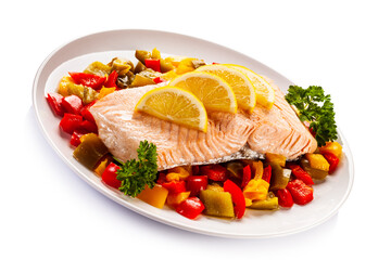 Roast salmon steak with mix of vegetables served on white background
