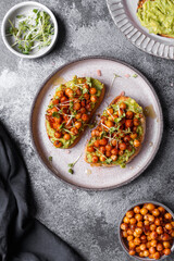 
bruschetta with avocado, chickpeas and microgreens on a dark background