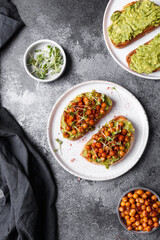 
bruschetta with avocado, chickpeas and microgreens on a dark background