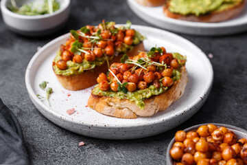 bruschetta with avocado, chickpeas and microgreens on a dark background
