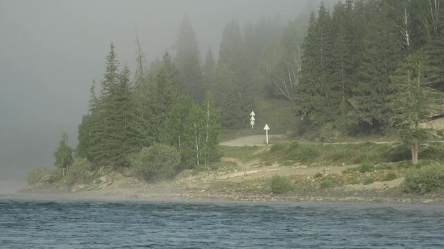 Video of river Katun, forest and road on the bank. Early morning. Mist over water.
