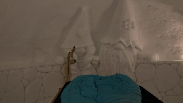 inside view of snow iglu with bed and beautiful carved art, ice carving two dwarfs into snow, zermatt ski resort