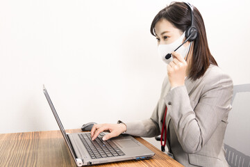 Woman wearing a headset with mask and having a web conference